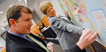 A student and faculty member pinning a map to a display board.